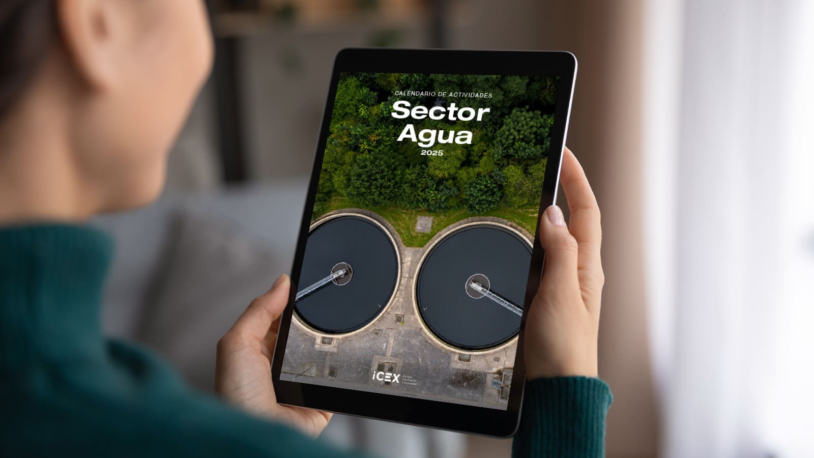 Una persona sujeta una tablet visualizando la portada del calendario de actividades del sector agua, ICEX