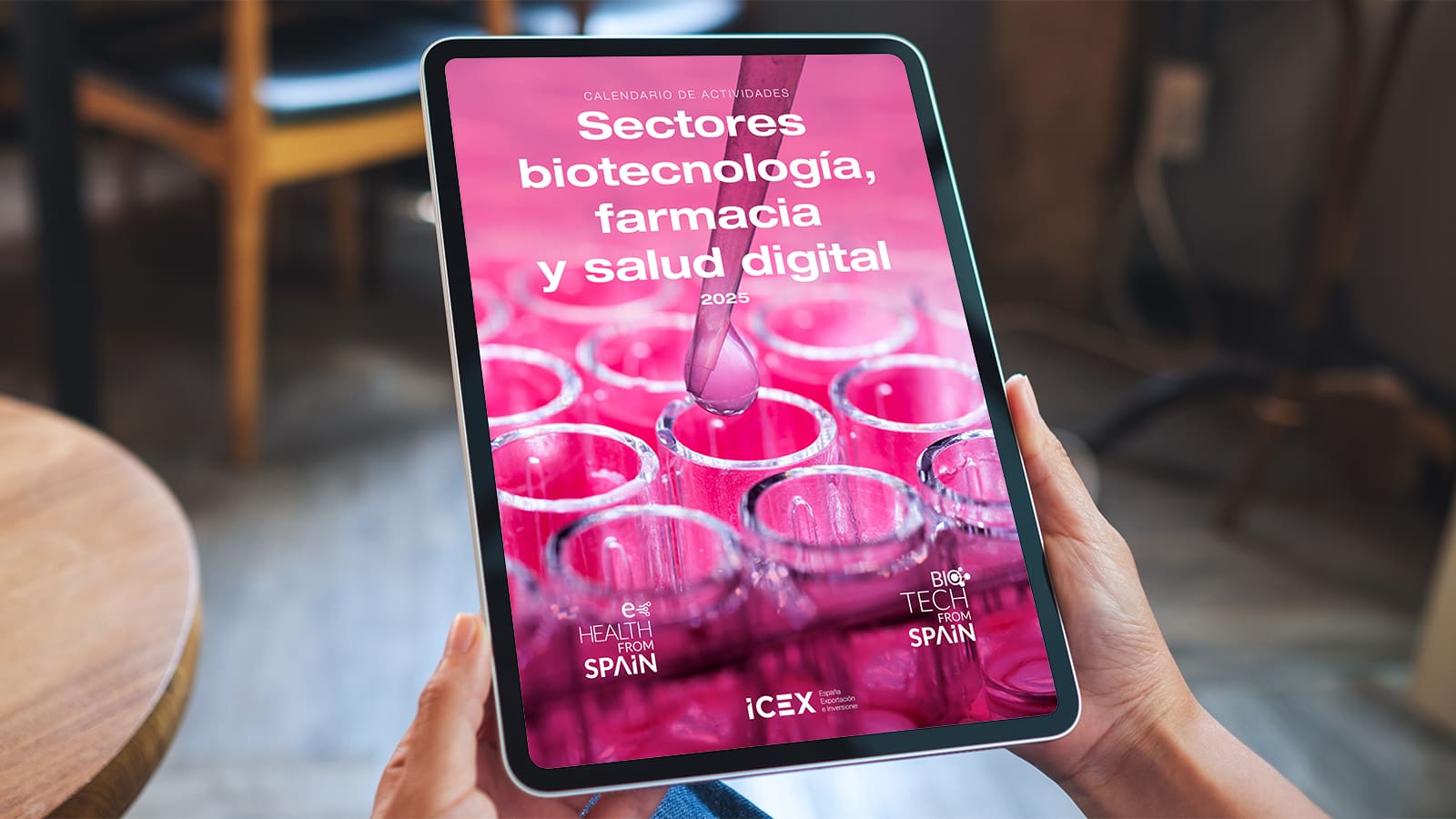 Una persona sostiene una tablet donde se visualiza el calendario de actividades para los sectores de biotecnología, farmacia y salud digital 2025