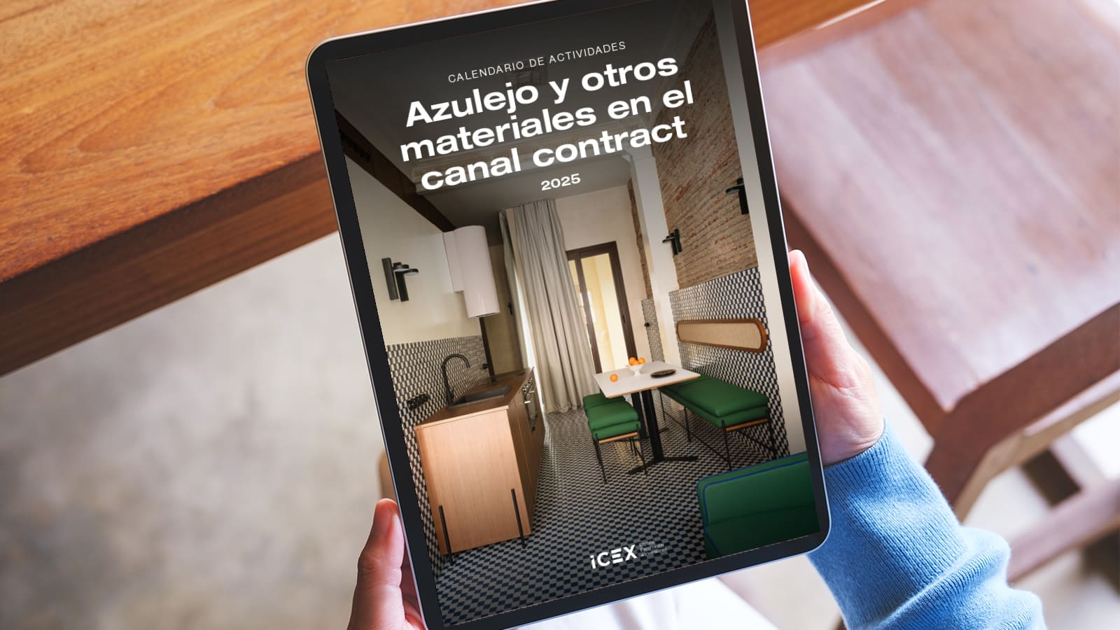Una persona sostiene una tablet donde visualiza la portada del calendario ICEX para canal contract 2025