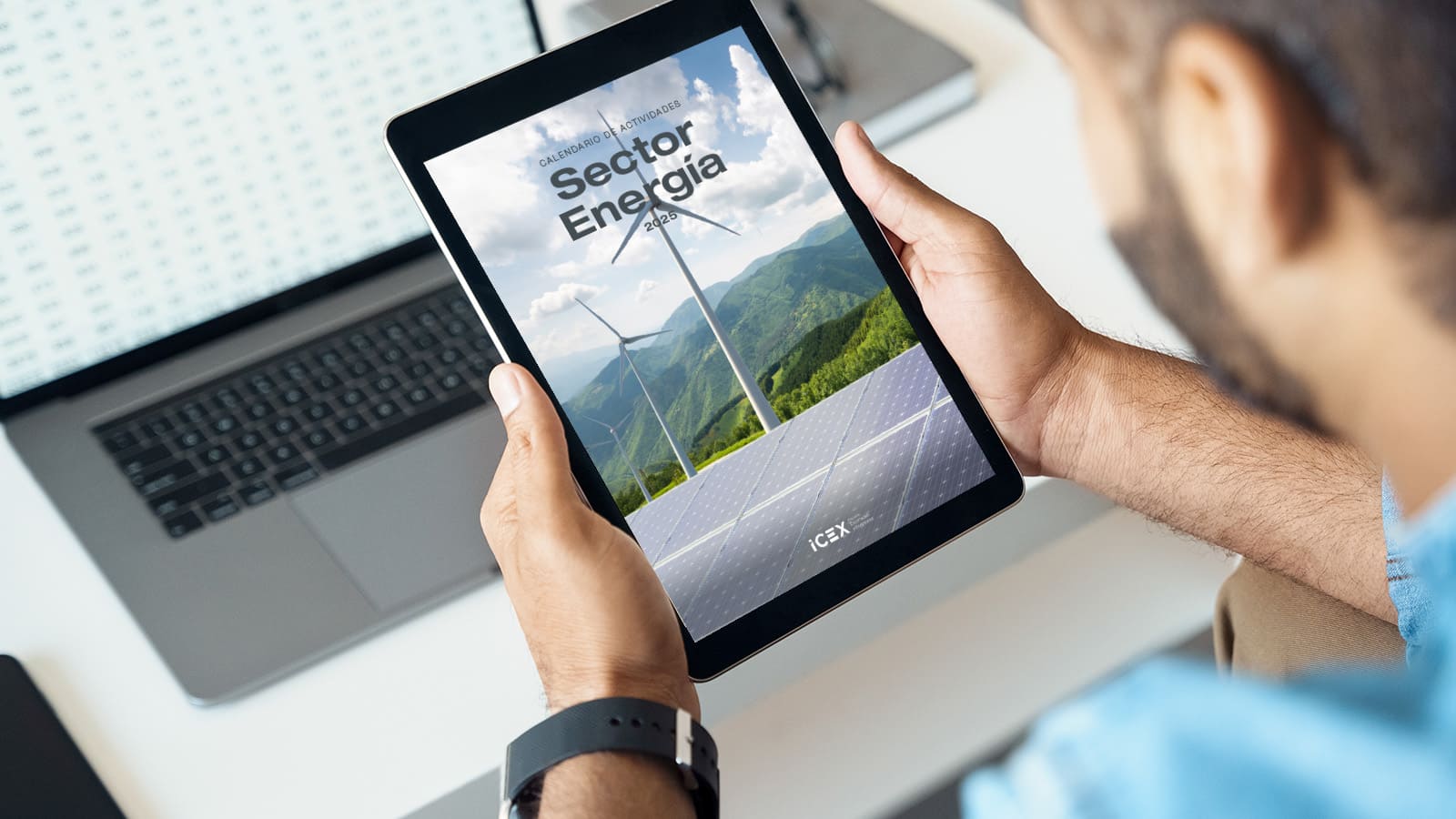 Un hombre sostiene una tablet donde visualiza el calendario ICEX para el sector energético