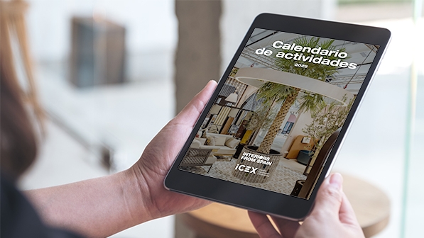 Una persona sostiene una tablet con la portada del calendario de actividades de ICEX para el sector hábitat