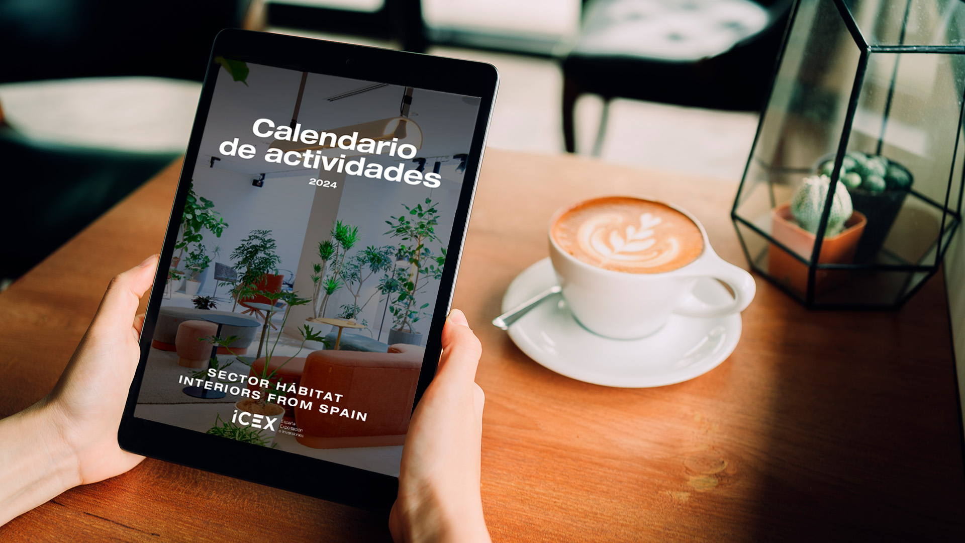 Una persona sostiene una tablet visualizando la portada del calendario de actividades del sector hábitat de Interiors From Spain, ICEX