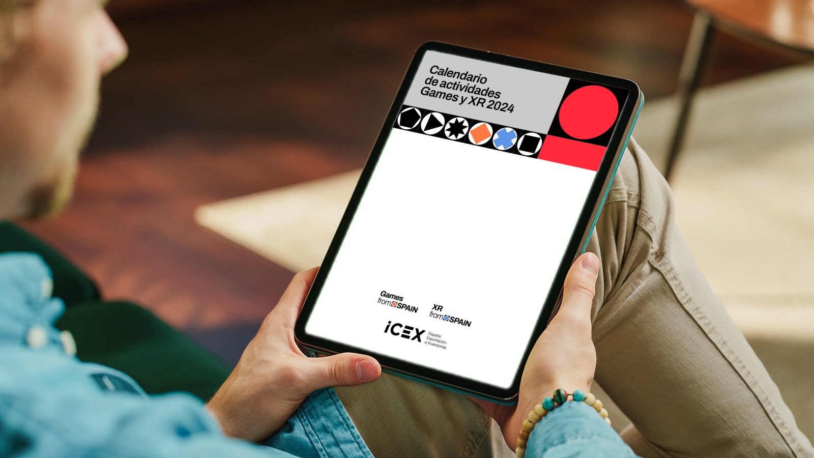 Una persona sostiene una tablet visualizando la portada del calendario de actividades del sector videojuegos y realidad extendida de Games From Spain y XR From Spain, ICEX