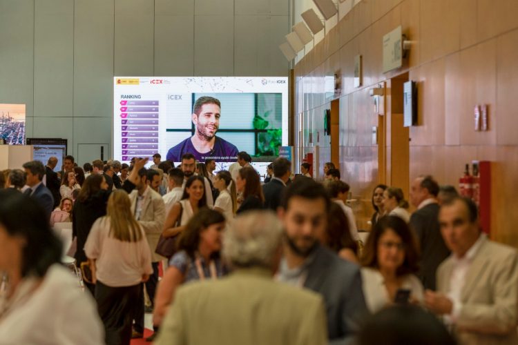 Un pabellón con gente y al fondo una pantalla grande con una persona