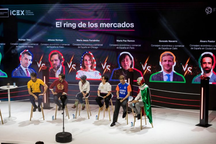 Seis personas sentadas en banquetas en un escenario disfrazadas