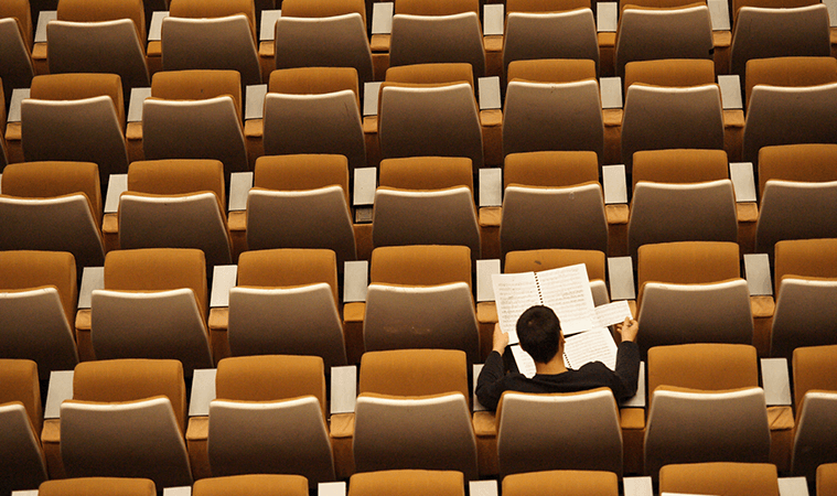 Hombre leyendo cuatro folios sentado en una butaca de un auditorio