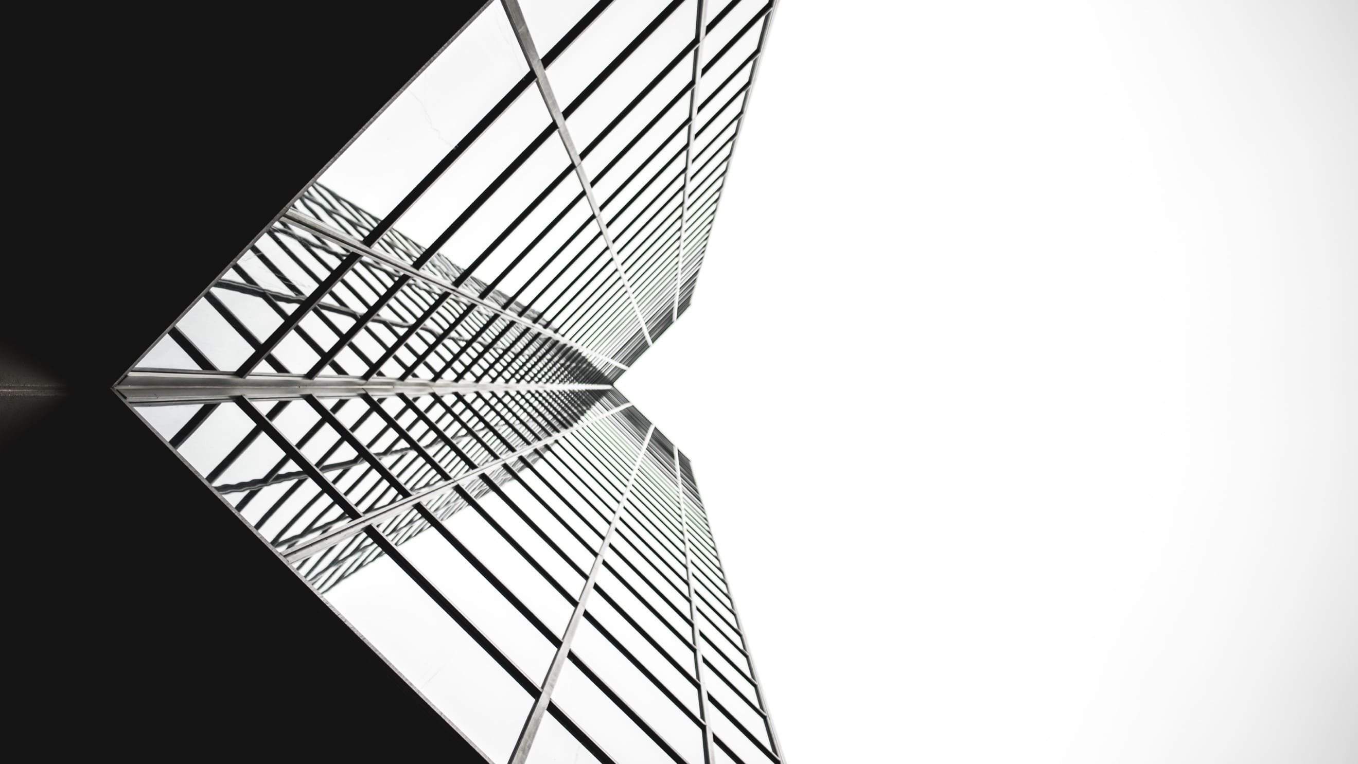 Imagen en blanco y negro de un edifcio visto desde abajo con espejos