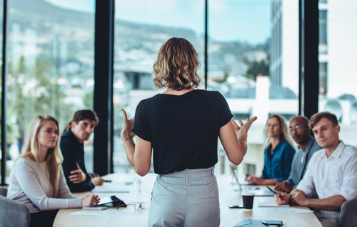 Reunión de trabajo liderada por una mujer woman explaining new strategies to coworkers during conference meeting in office. Businesspeople meeting in office board room for new project discussion.