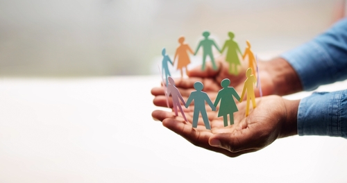 Manos sosteniendo recortes de personas de distintos colores. Diversidad en inclusión. 
