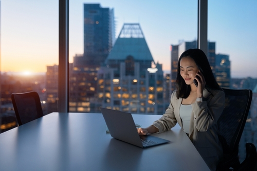 Joven mujer de negocios asiática trabajando en su oficina al anochecer