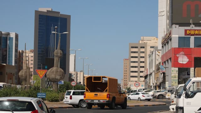 coches y furgoneta blanca en una calle de la ciudad de Kuwait