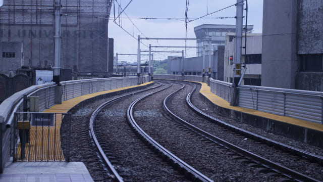 Vías de tren vacías con cables tendidos en día con niebla