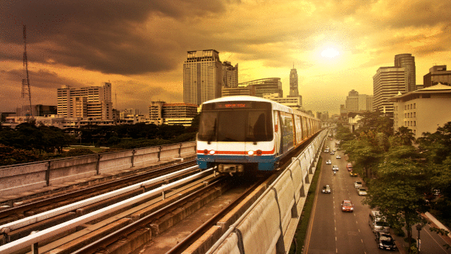 Tren en vías al atardecer con ciudad de grande edificios al fondo