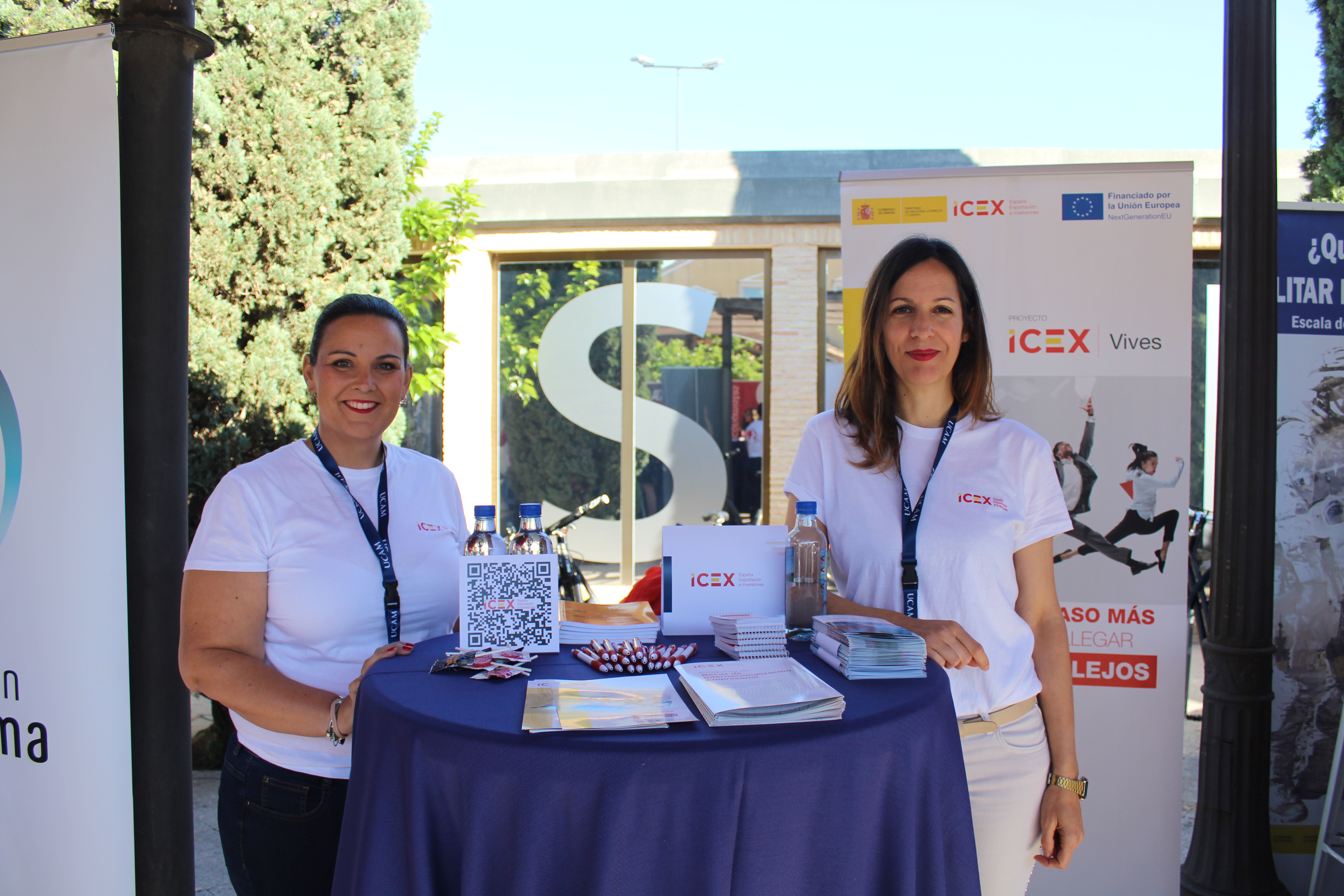 Dos personas de pie tras una mesa alta donde muestran folletes informativos sobre ICEX España Exportación e Inversiones