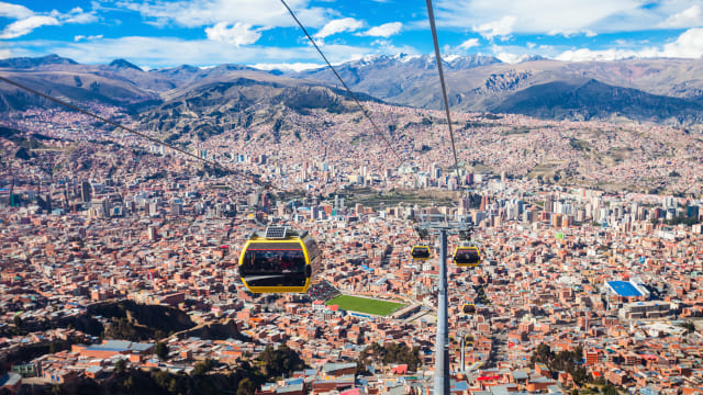 Teleférico bajando por cable sobre la ciudad de la Paz y al fondo Los Andes