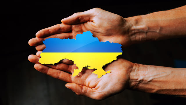 Dos manos sujetando un mapa de Ucrania con los colores de la bandera
