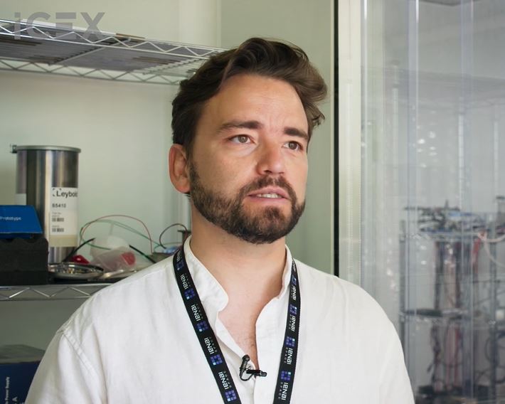 Hombre con camisa blanca y colgante con acreditación, uno de los cofundadores de IENAI Space, nos cuenta su experiencia en Space Tech Expo con ICEX