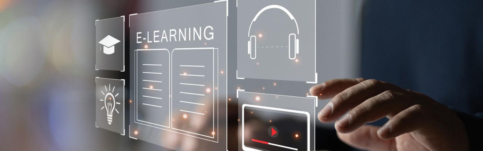 Una mano toca un holograma en el que aparecen unos auriculares, un libro, la palabra e-learning, un birrete y una bombilla.