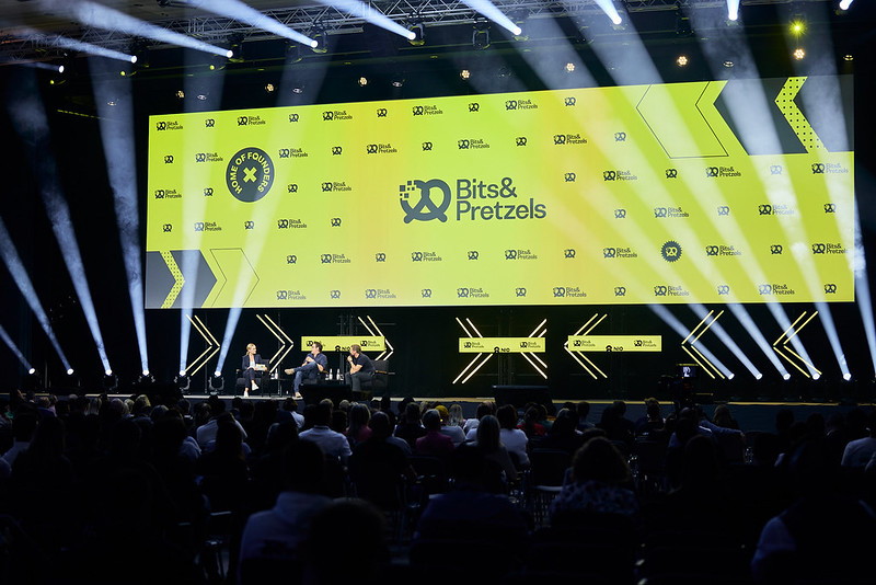 Varios ponentes conversan en una mesa redonda ante una gran cantidad de público en un escenario de Bits and Pretzels
