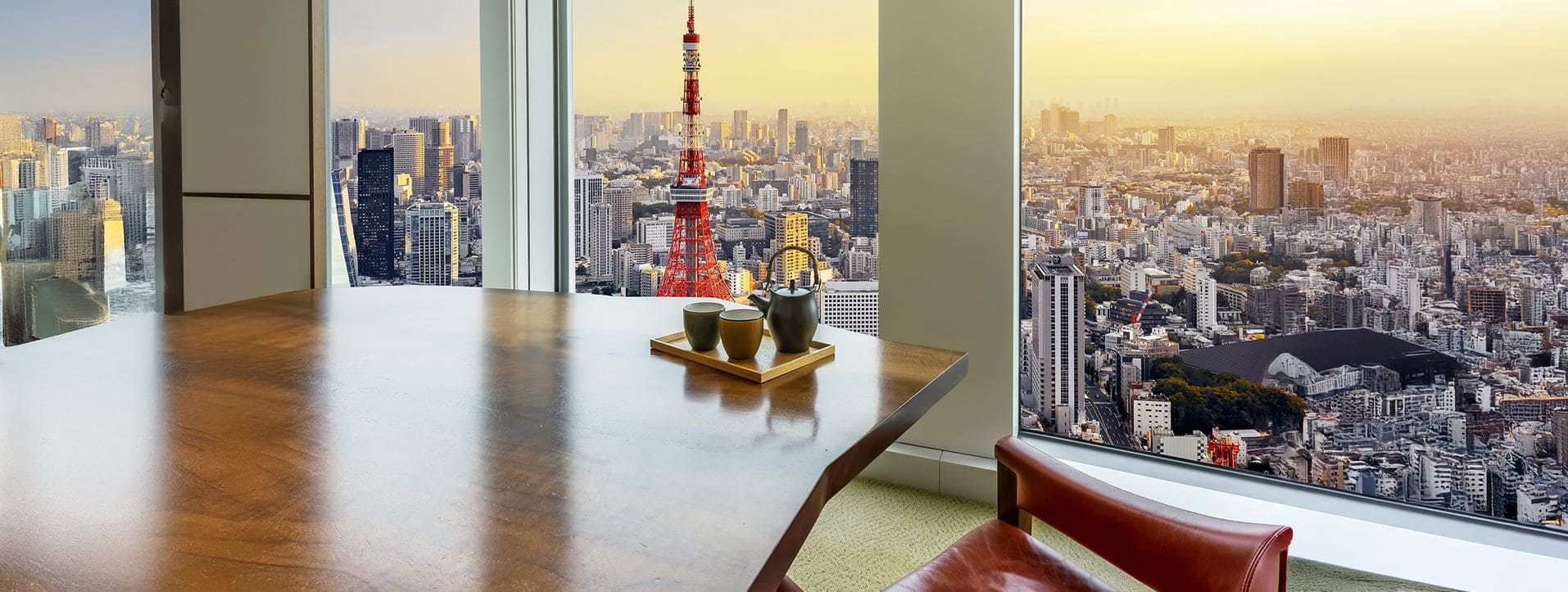 Una oficina con una mesa de reuniones de madera y unos ventanales desde los que se ve la ciudad de Tokio desde las alturas