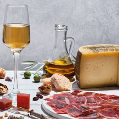 Cotillón que incluye un plato de jamón ibérico, un queso, una jarra con aceite de oliva virgen extra y una copa de vino blanco.