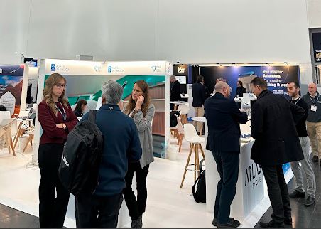 Dos grupos de personas mantienen conversaciones delante del stand de una empresa en el Pabellón España de Xponential Europe.