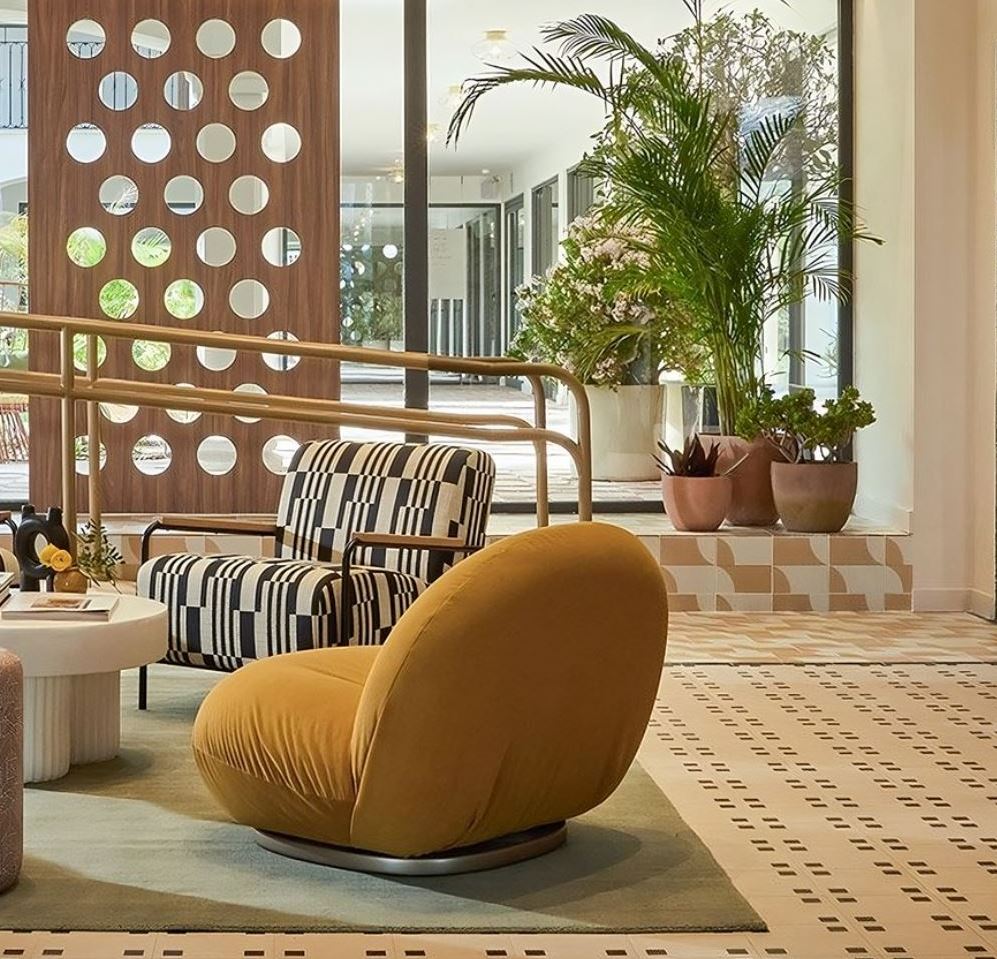 Salón con muebles de diseño y un pavimento de color rosado con cuadros marrones.