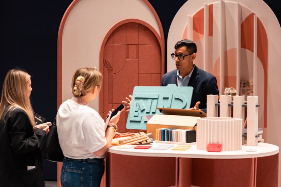 Un expositor muestra productos de diseño a dos visitantes polacas.