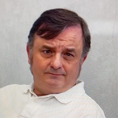 Retrato en primer plano de un hombre con cabello corto y oscuro, vestida con polo claro. Fondo neutro y liso. La iluminación suave destaca el rostro y sus rasgos definidos con mirada directa.