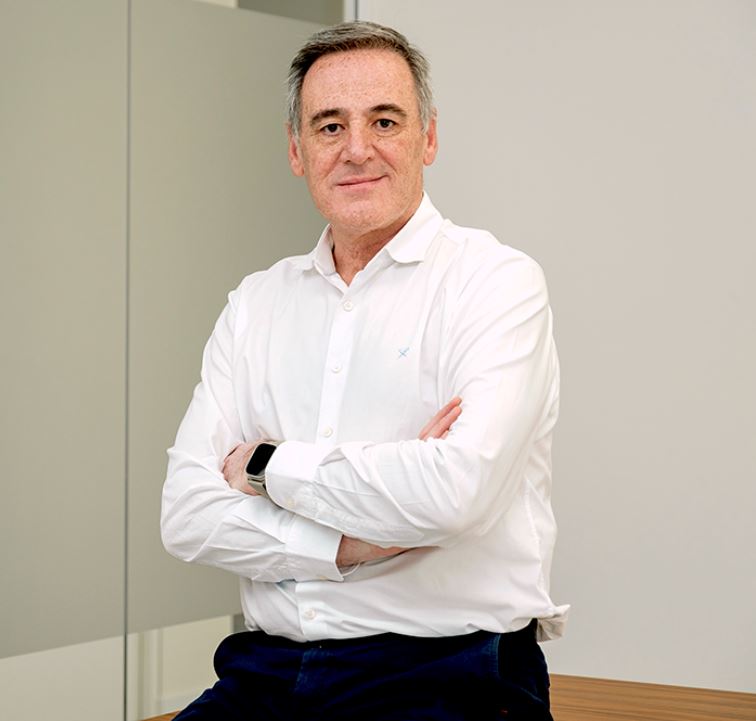 Julio Roda posa ante la cámara con los brazos cruzados, viste con camisa blanca, pantalón negro y un smartwatch.