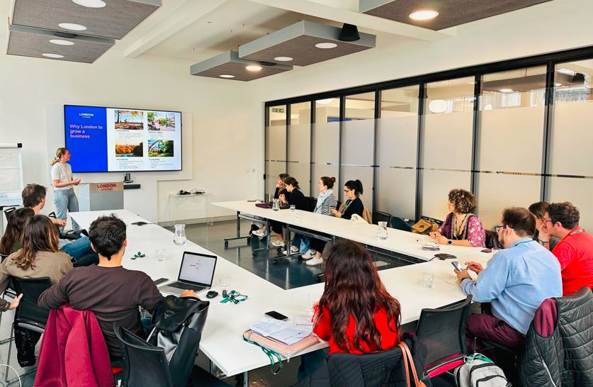 Varias personas se sientan en una mesa de una sala de reuniones de la Oficina Económica y Comercial de España en Londres para ver una presentación sobre el mercado británico.