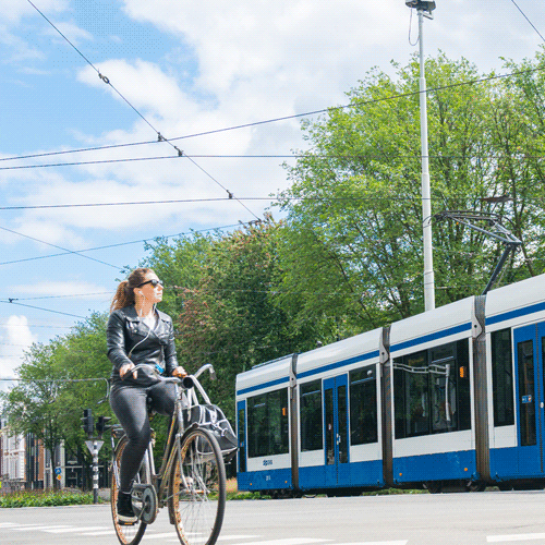 A la izquierda viajan varias personas en bicicleta, y a su derecha transita un tranvía con carrocería blanca y azul