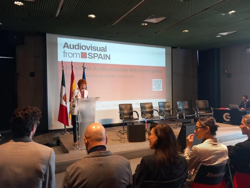 Presentación de la Consejera Económica y Comercial de España en México ante un público de muchas personas en un auditorio.