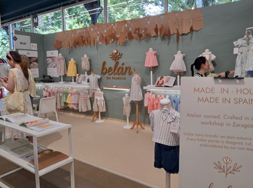 Un stand con un showroom de prendas de vestir, calzado y complementos de moda infantil, dentro de Playtime II París.