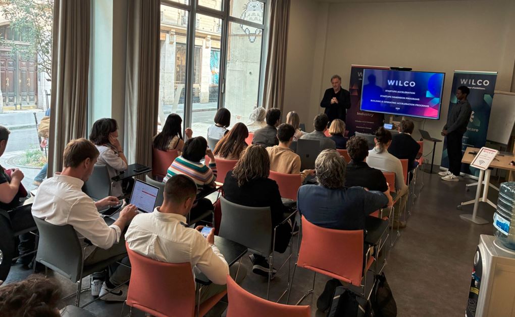 Dos representantes de una startup realizan un pitch con presentación en un monitor incluida, ante decenas de personas en una sala