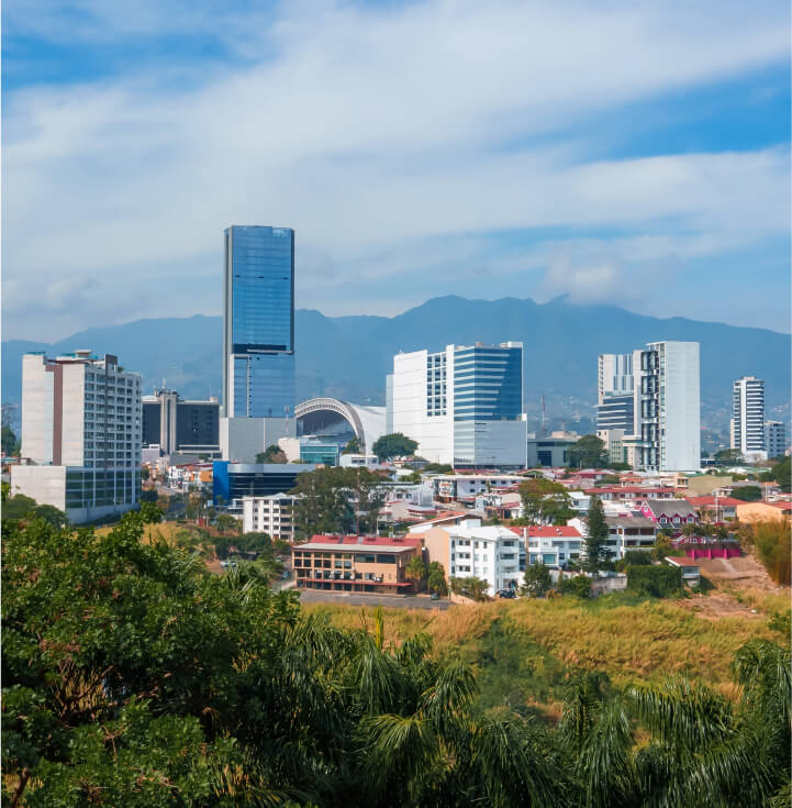 árboles en primer plano y edificios de oficinas al fondo en San José de Costa Rica