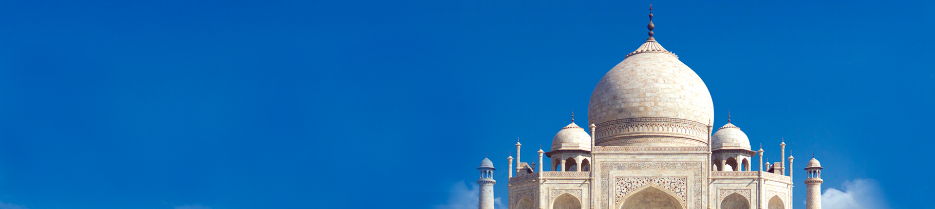 Cúpula y minarete del Taj Mahal en Agra, India, sobre un fondo de cielo claro.