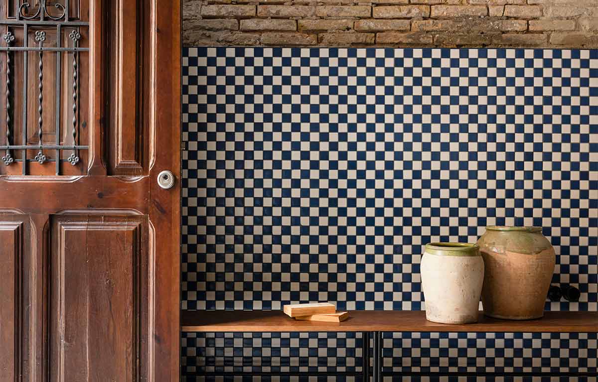 pared de azulejos damero con dos vasijas sobre un banco