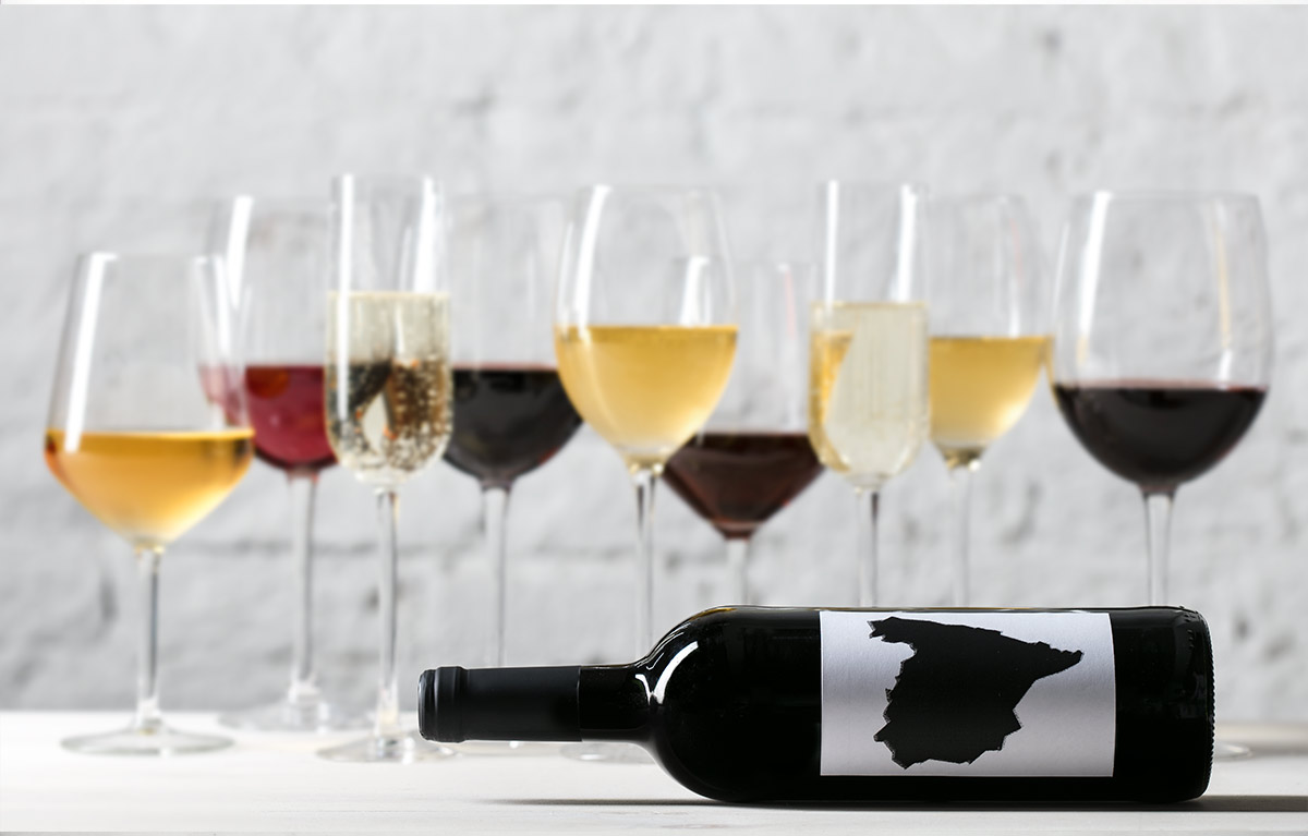 copas de varios tipos de vino con una botella tumbada con una etiqueta con la península ibérica en color negro