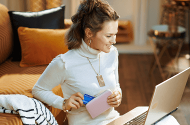 Mujer ante un ordenador saca la tarjeta de crédito de su monedero
