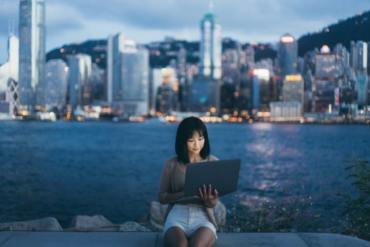 Imagen ilustrativa para la noticia "El ecosistema digital que manda en China en 2026: cinco plataformas clave para las marcas", que muestra una joven con un ordenador portátil con rascacielos al fondo.