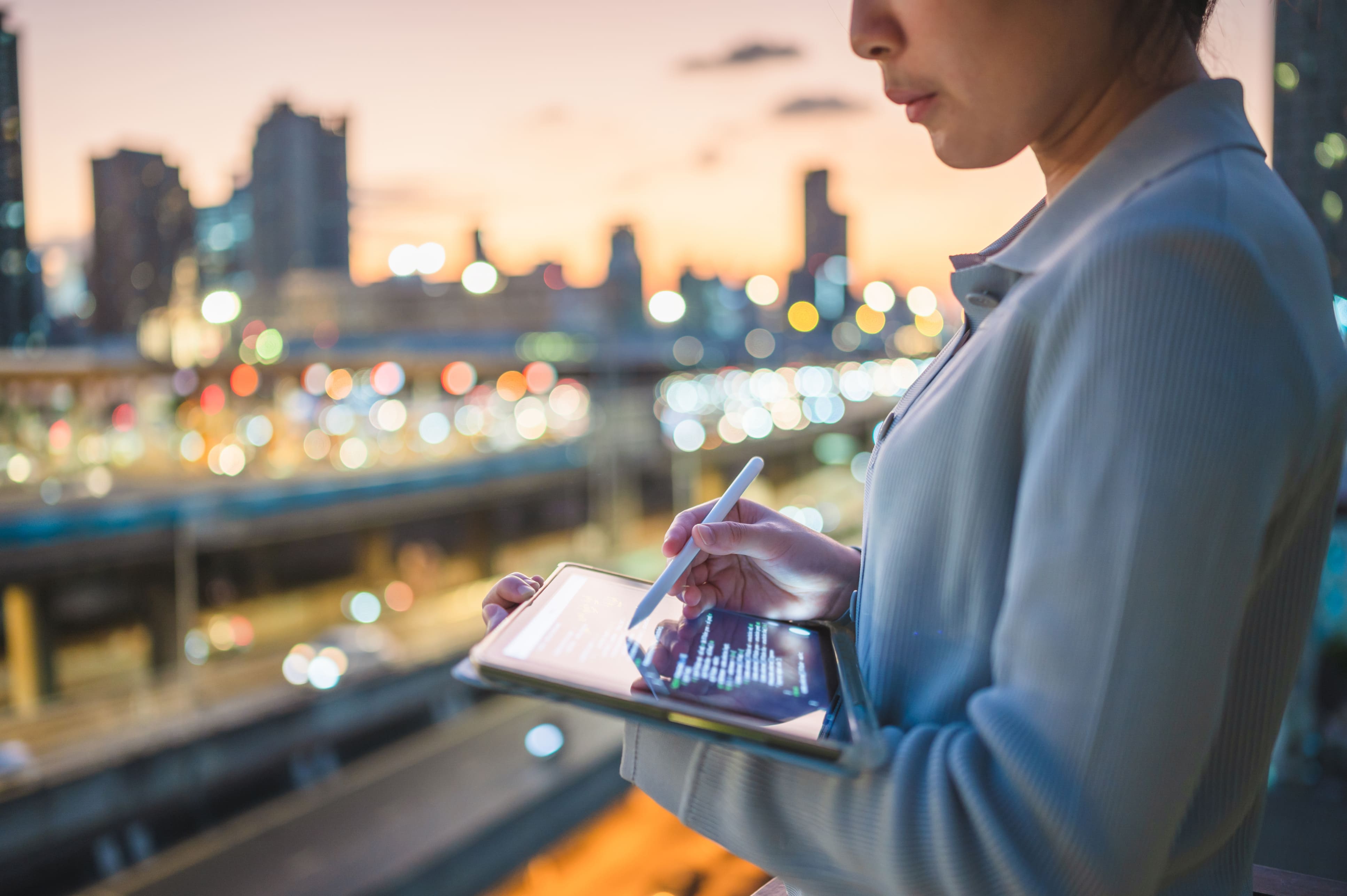 Imagen ilustrativa para la noticia "La IA impulsa el ascenso de Naver en Corea". Muestra una mujer escribiendo en una tablet con un lápiz digital, con la ciudad al atardecer de fondo.