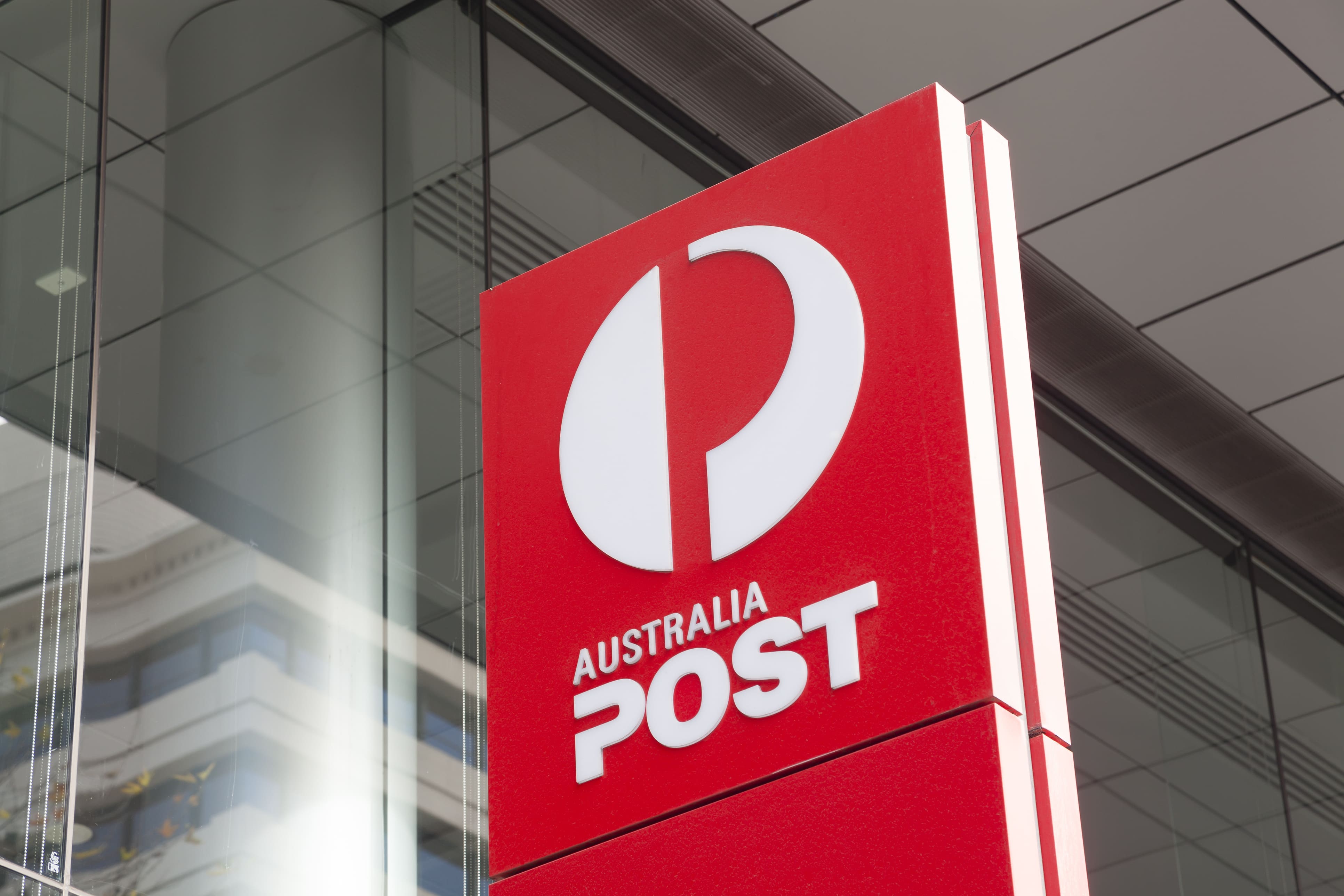 Imagen ilustrativa para la noticia "Australia Post acelera la carrera por el same day delivery con la adquisición de Rendr". Muestra el logo de Australia Post en la fachada de un edificio.