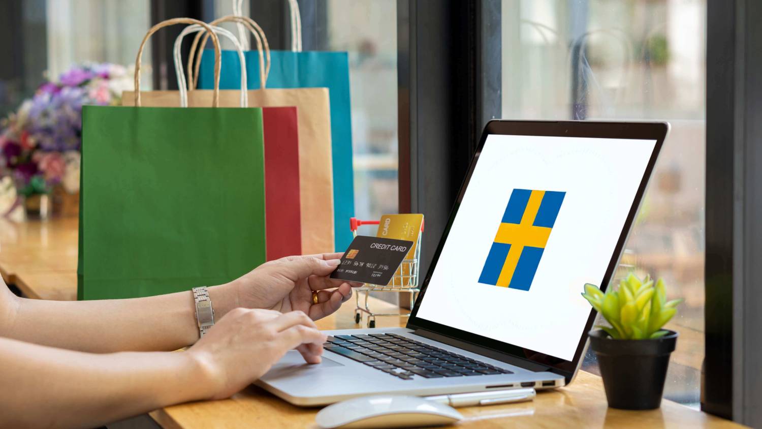Un consumidor online de Suecia sostiene una tarjeta de crédito frente al ordenador