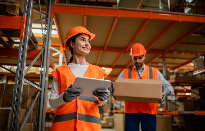 dos personas con cascos naranjas de obra y chalecos naranjas