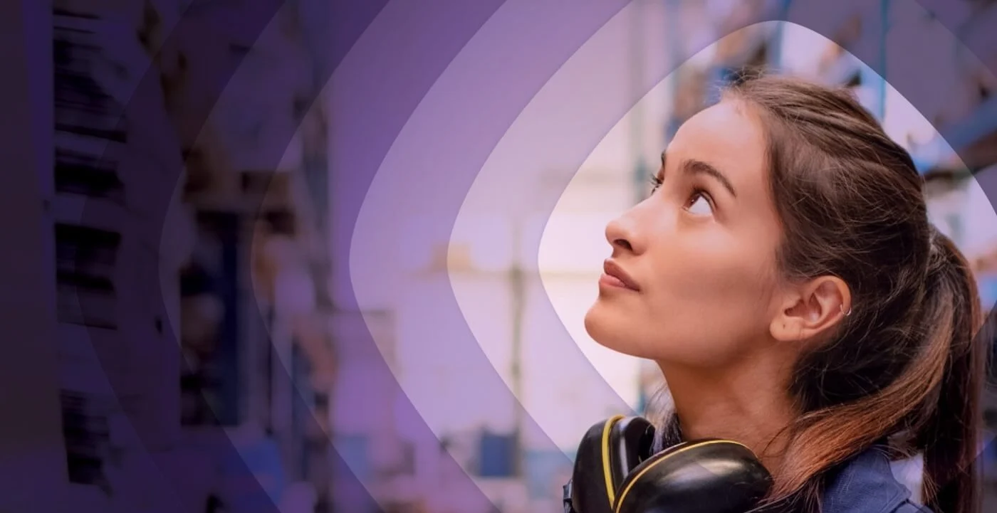 Banner que muestra a una mujer mirando hacia arriba a algo fuera de campo. Lleva auriculares, y la imagen está editada de forma que muestra un degradado morado de más claro a más oscuro rodeándola.