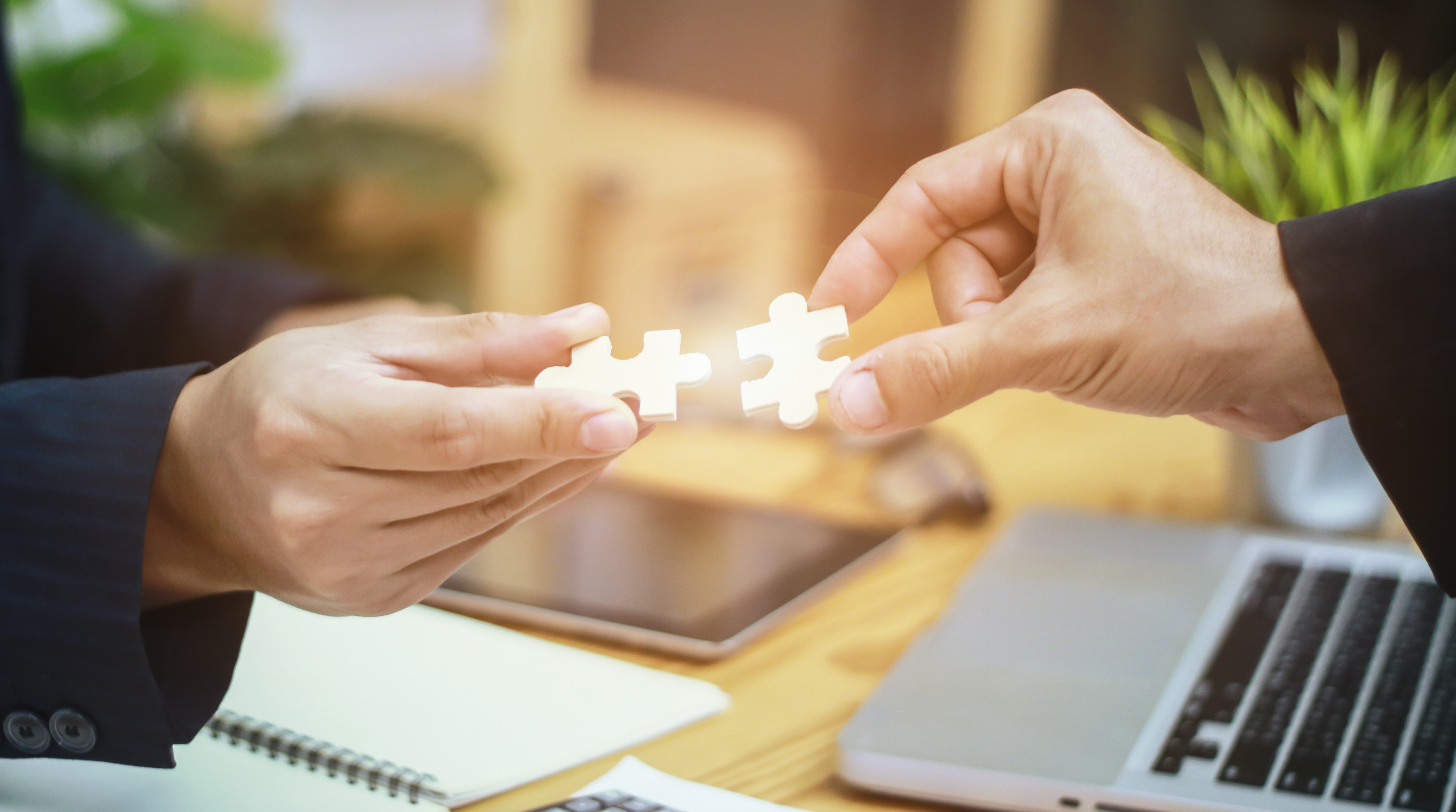 Imagen para el reportaje "Dar el salto de la conciliación a la corresponsabilidad", que muestra dos manos de dos personas diferentes uniendo dos piezas de puzzle.