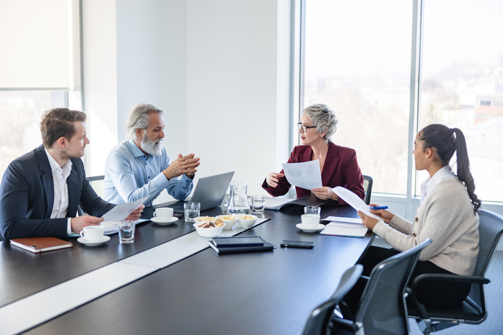 Una empresaria dirigiéndose a sus colegas en una reunión de la junta directiva.