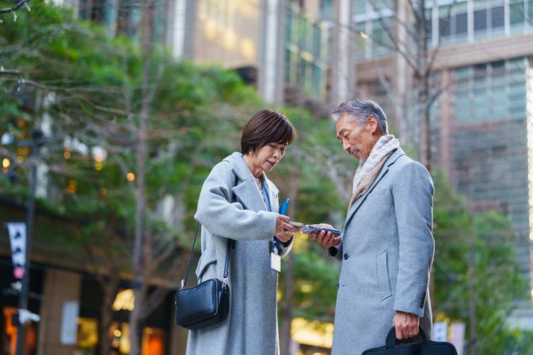 Imagen ilustrativa para el reportaje sobre manual para directivas interesadas en el mercado japonés. Muestra dos compañeros de trabajo intercambiando información en sus teléfonos móviles.