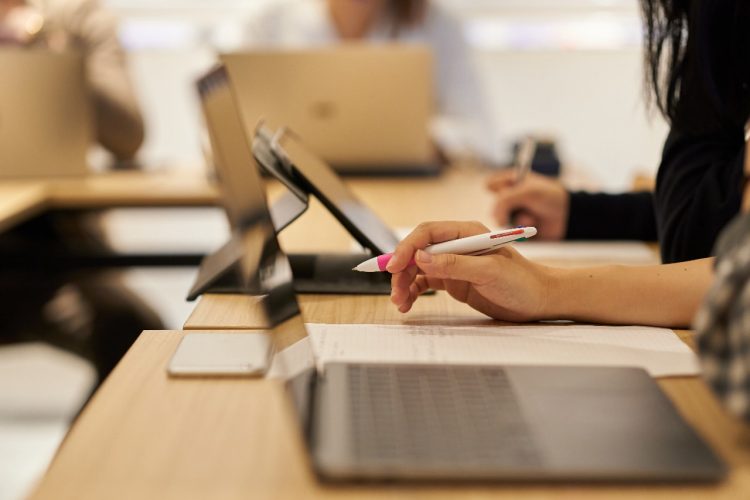 Imagen ilustrativa para el reportaje sobre manual para directivas interesadas en el mercado japonés. Muestra dos personas escuchando un seminario, con la imagen centrada en sus manos tomando notas.